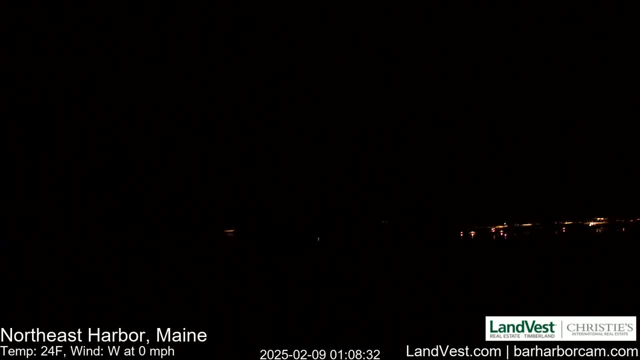 A dark nighttime scene shows a distant line of faint lights across the bottom of the image, with a calm, 24°F temperature and no wind.