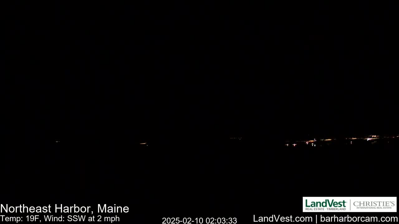 A dark nighttime scene shows a faint line of distant lights on the horizon under a clear, black sky, with a temperature of 19 degrees Fahrenheit and a southwest wind of 2 mph.