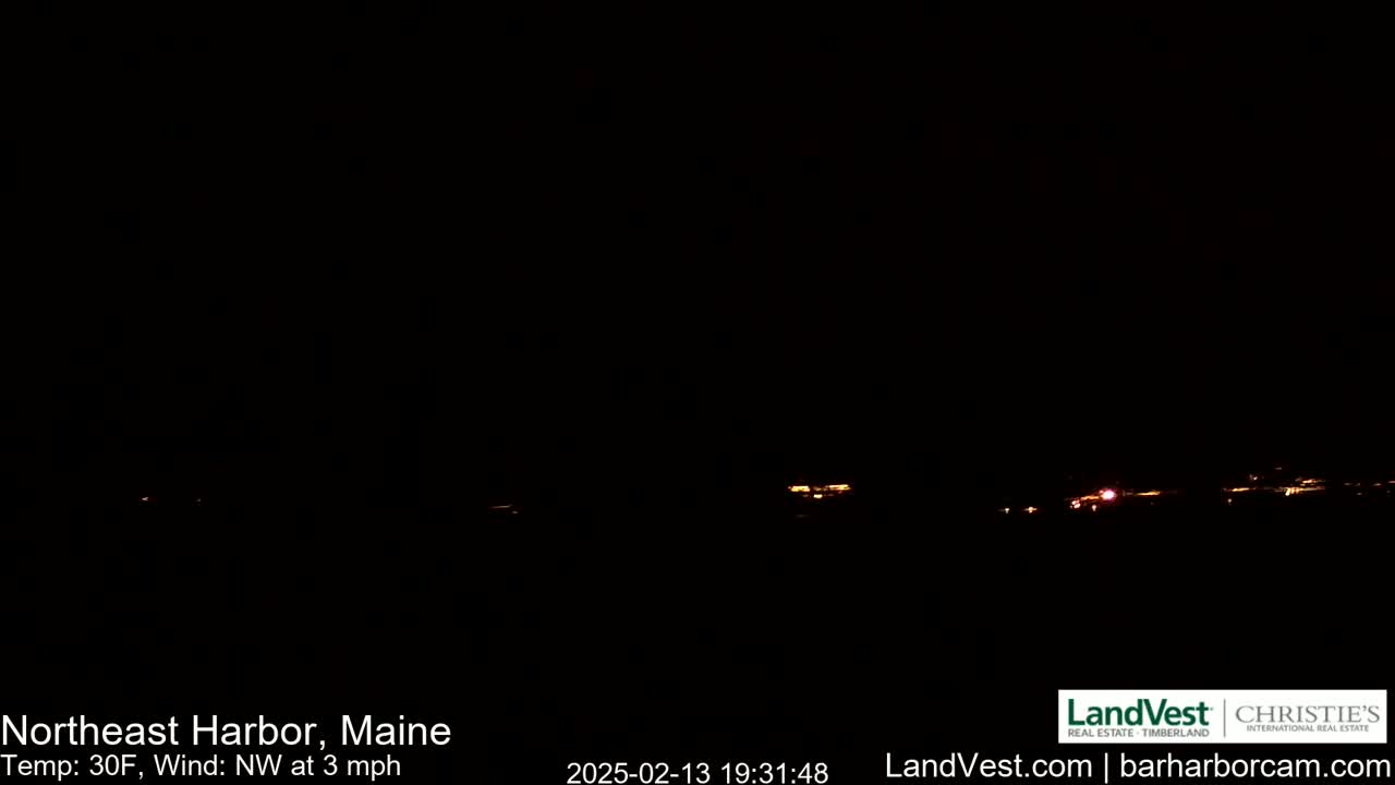A dark, nighttime scene shows a distant line of faint lights under a clear, black sky with a temperature of 30°F and a northwest wind of 3 mph.