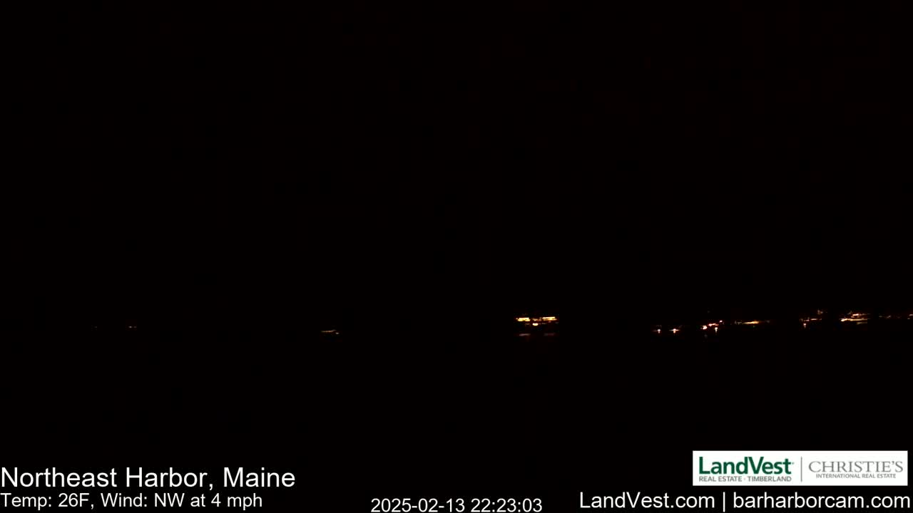 A dark nighttime scene shows a faint line of distant lights across the horizon under a clear, dark sky, with a northwest wind blowing at 4 mph and a temperature of 26 degrees Fahrenheit.