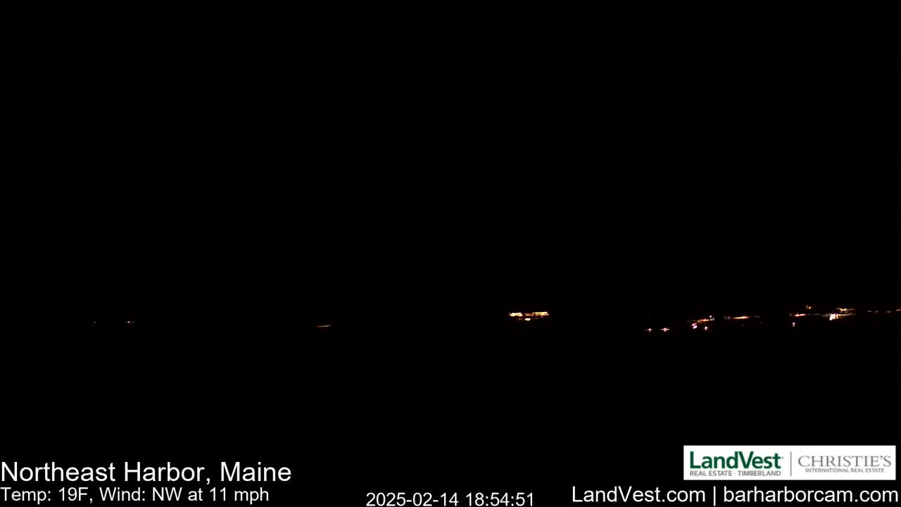 A nighttime long shot shows a dimly lit town on a dark horizon under a clear, cold sky with a northwest wind.