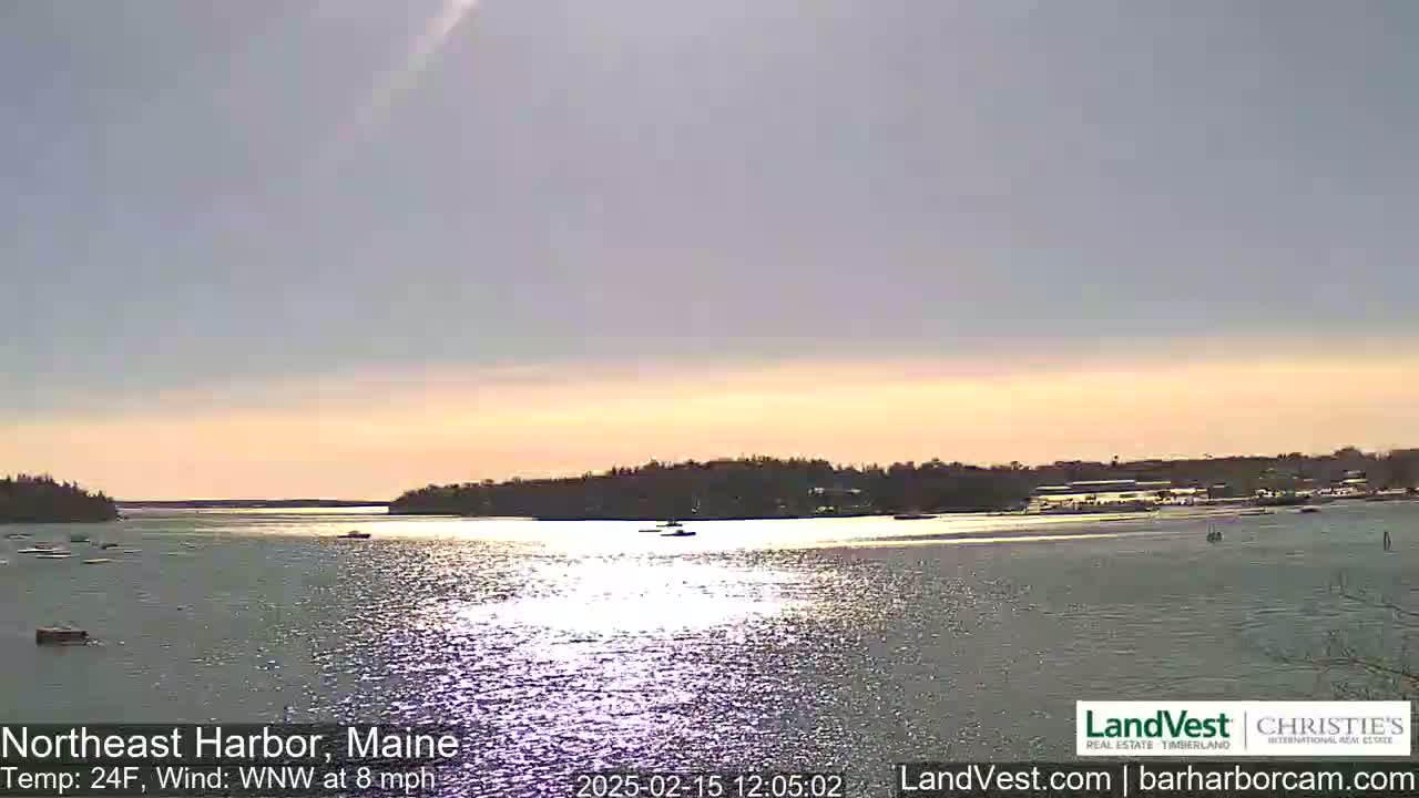 A calm body of water reflects the sunlight under a mostly clear, pale sky, with a landmass visible in the distance.