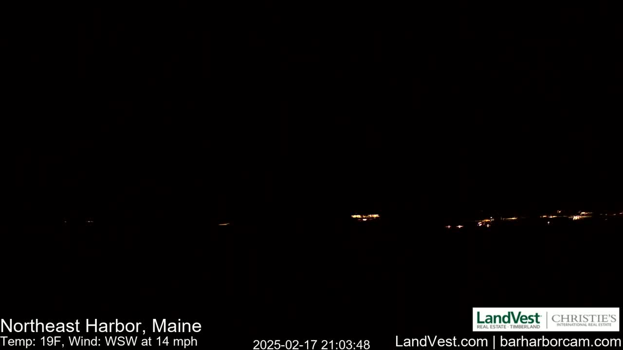 A dark nighttime scene shows a faint line of lights in the distance under a clear, dark sky, with a temperature of 19°F and a wind of 14 mph from the west-southwest.