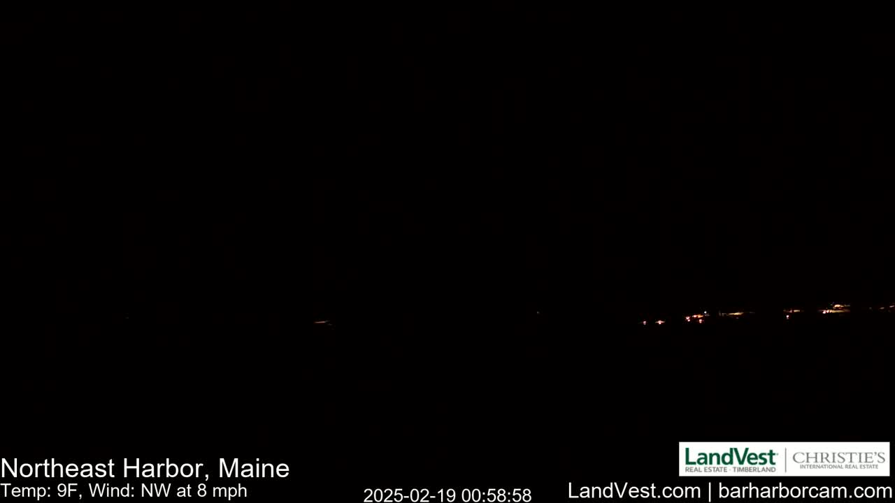 A nighttime long shot of a dimly lit town under a dark, clear sky with a northwest wind at 8 mph and a temperature of 9°F.
