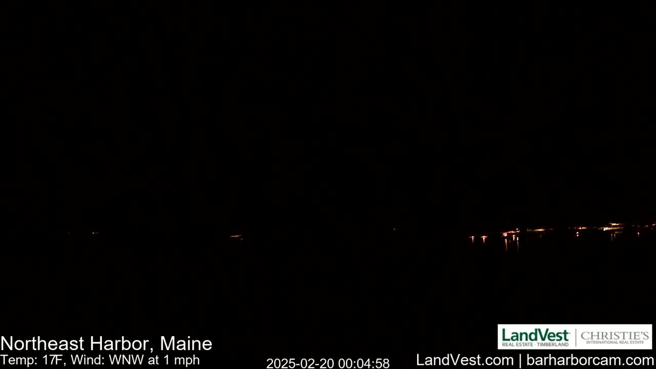A dark nighttime scene shows a body of water with faint lights on the far shore under a clear, dark sky, with a temperature of 17°F and a light west-northwest wind.