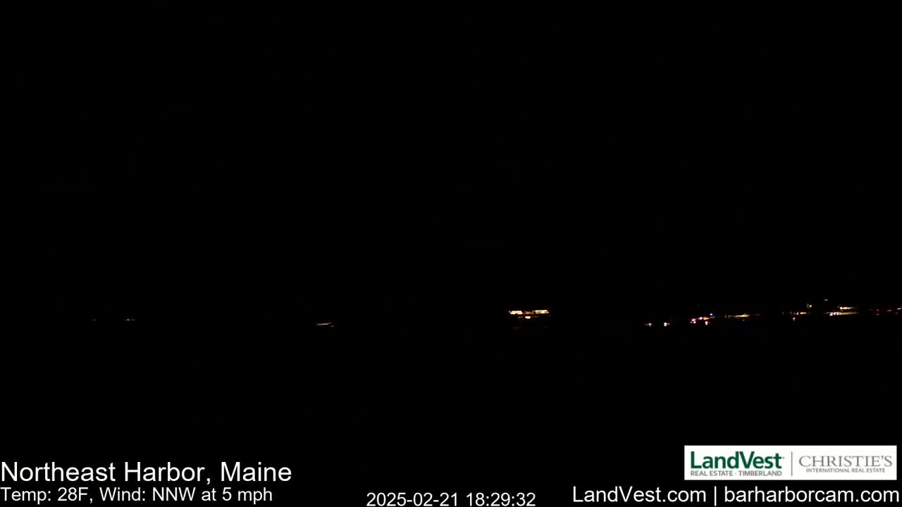 A nighttime long shot of a dimly lit town or village under a dark, clear sky with a temperature of 28°F and a north-northwest wind at 5 mph.