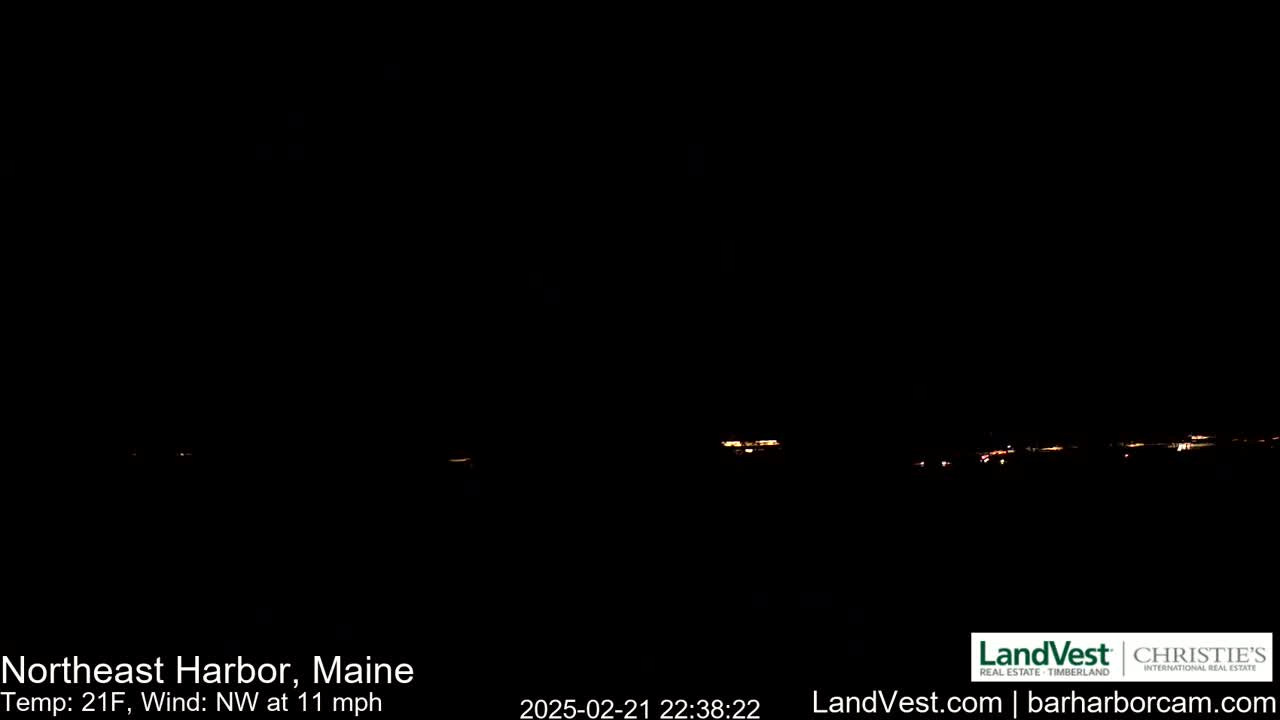 A nighttime, long shot of faintly visible lights from a distant town under a dark, clear sky with a temperature of 21°F and a northwest wind of 11 mph.