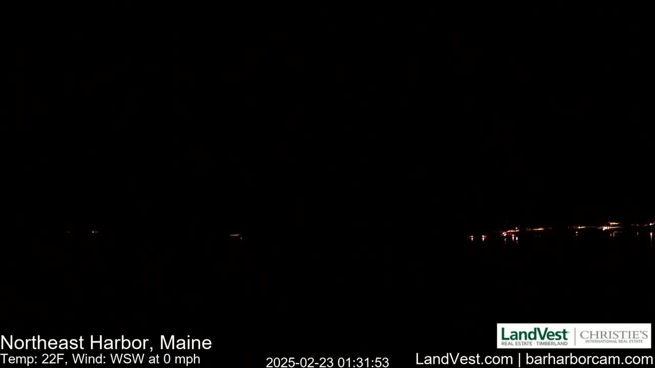 A dark nighttime scene shows a faint line of lights on the horizon, with a calm, 22°F wind.