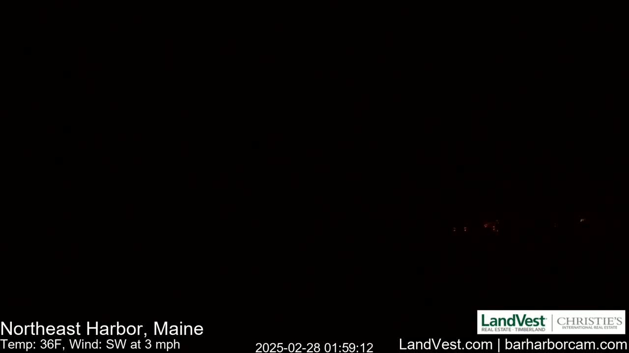 A nighttime, low-light image shows a few distant, faint lights in the darkness with a 36°F temperature and a southwest wind of 3 mph.