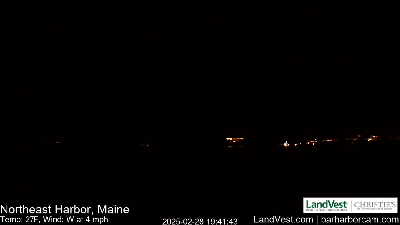 A nighttime long shot shows a dark, mostly black scene of a sparsely lit town under a clear, dark sky, with a 27°F temperature and a 4 mph westerly wind.