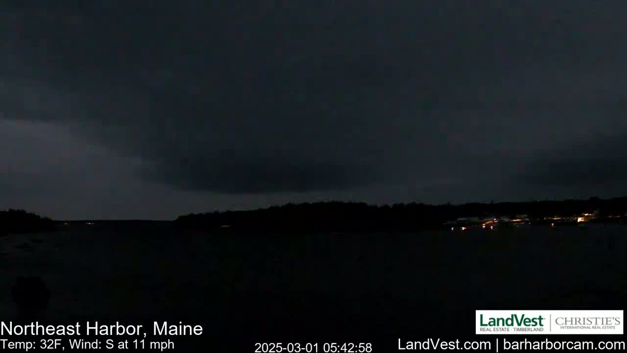 A dark, nighttime scene shows a body of water with a distant shoreline under an overcast sky, with a south wind at 11 mph and a temperature of 32°F.