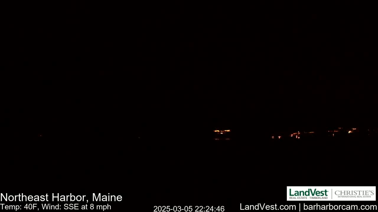 A dark nighttime scene shows a distant line of faint orange lights across a black horizon under a dark sky, with a SSE wind at 8 mph and a temperature of 40°F.