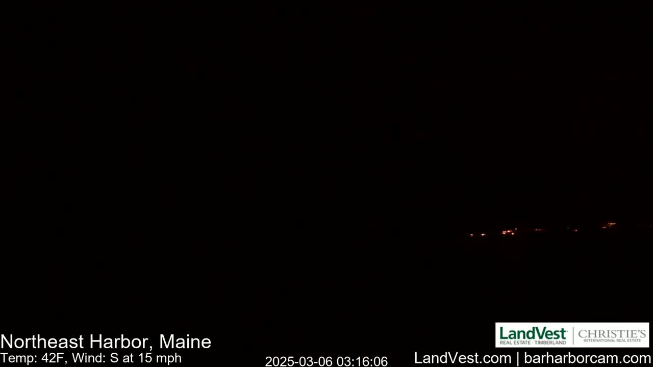 A dark nighttime scene shows a few distant, faint lights on the horizon under a clear, dark sky; a south wind blows at 15 mph with a temperature of 42°F.