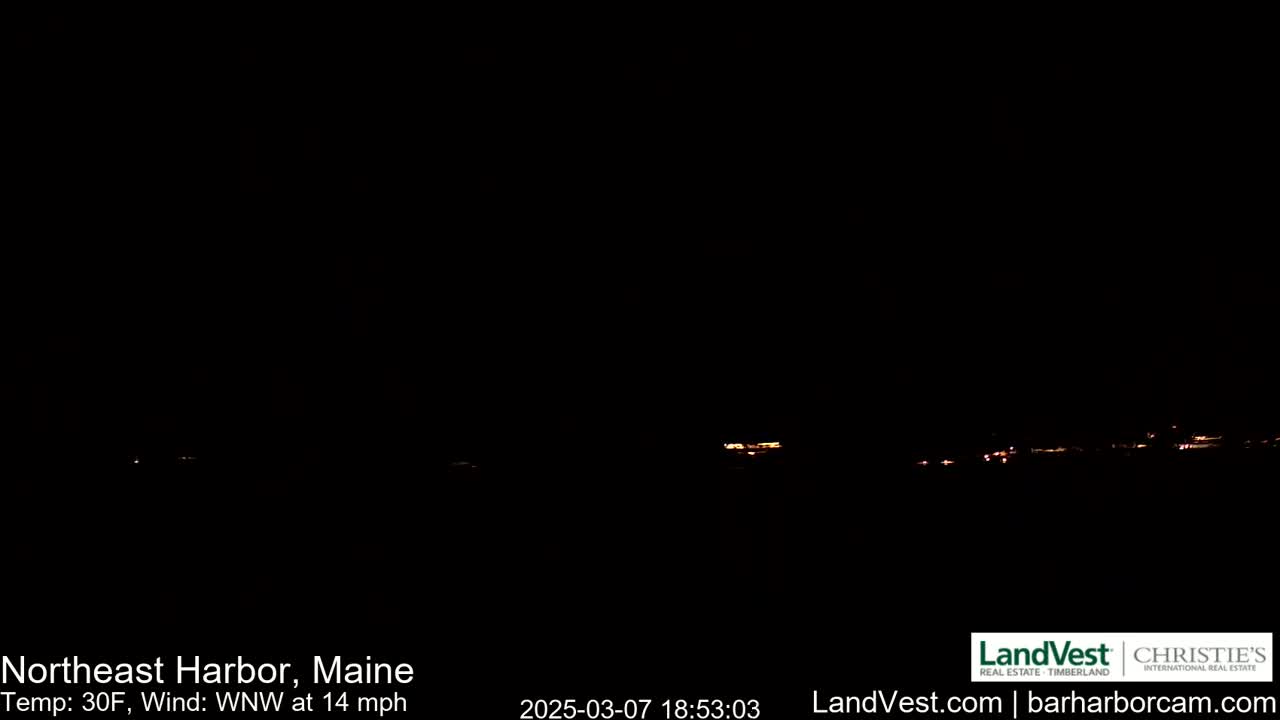 A dark nighttime scene shows a faint line of distant lights on the horizon under a clear, black sky with a 30°F temperature and a 14 mph wind from the west-northwest.