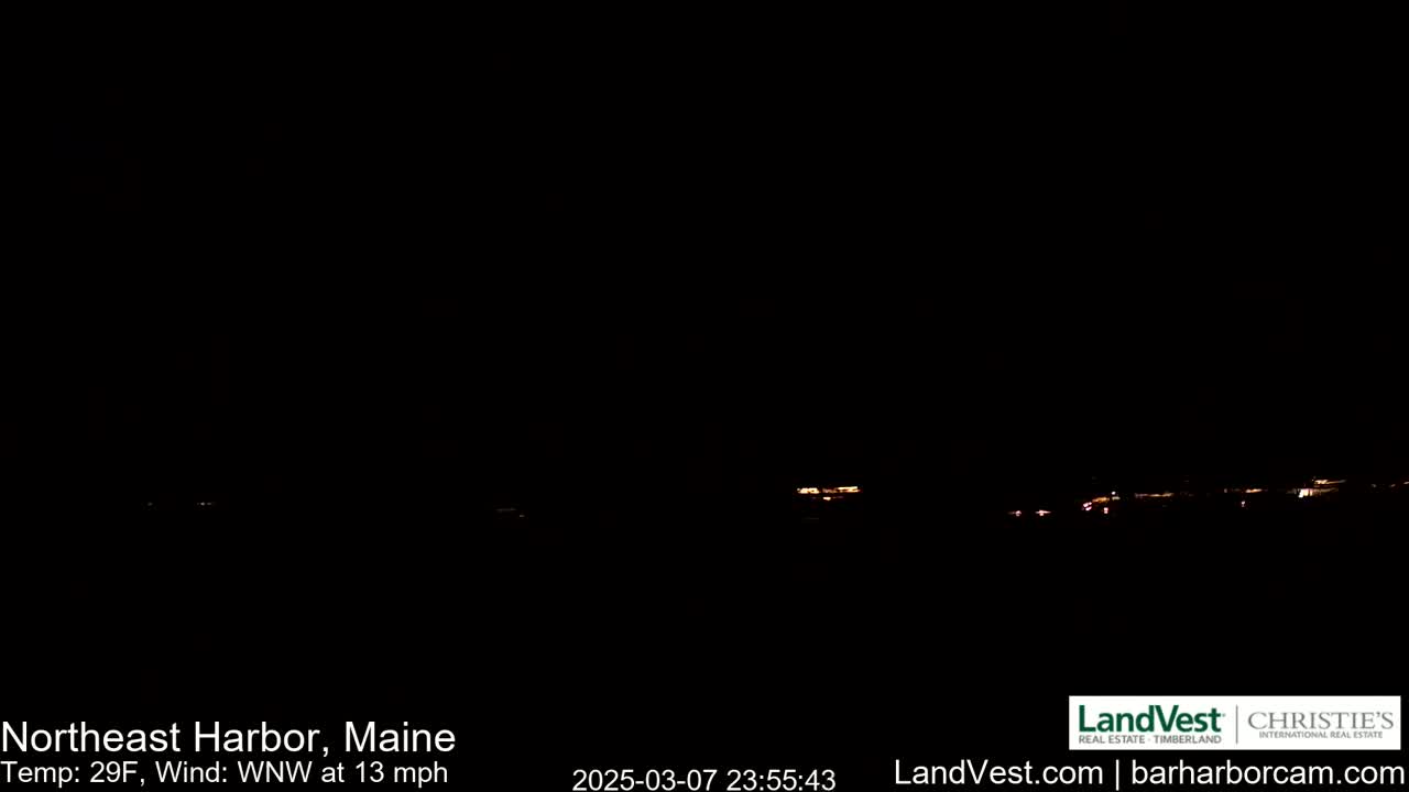 A nighttime long shot shows a dark landscape with a few faint lights on the horizon under a clear, dark sky, with a 29°F temperature and a 13 mph wind from the west-northwest.