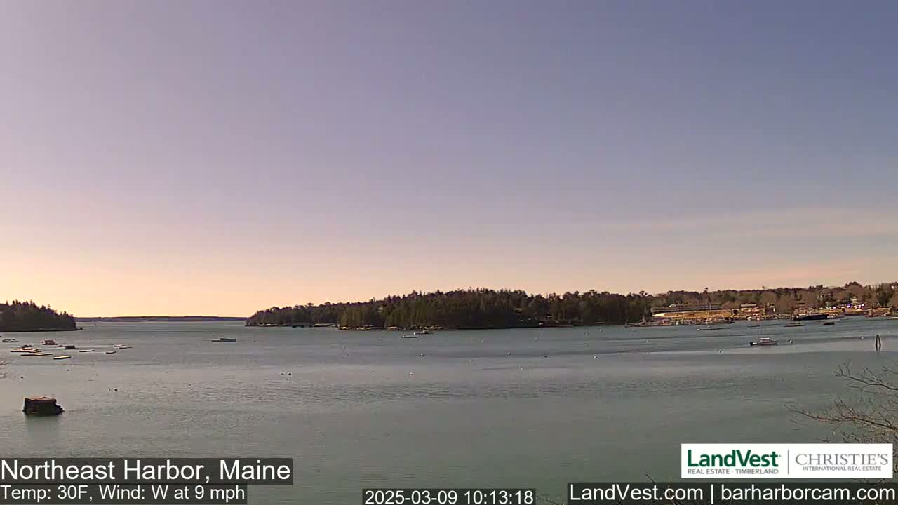 A calm harbor with several boats is seen on a partly sunny day with a 30°F temperature and a 9 mph west wind.