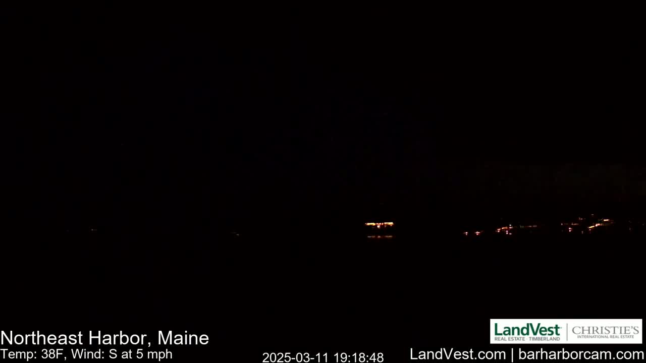 A dark nighttime scene shows a few distant lights across a body of water under a clear, dark sky with a south wind at 5 mph.