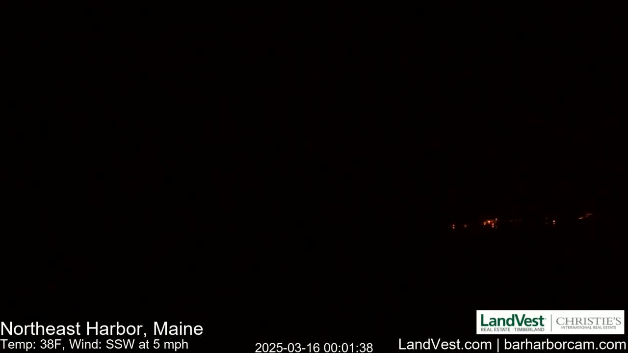 A nighttime long shot shows a dark landscape with a few faint lights visible in the distance under a dark sky, with a temperature of 38°F and a south-southwest wind at 5 mph.