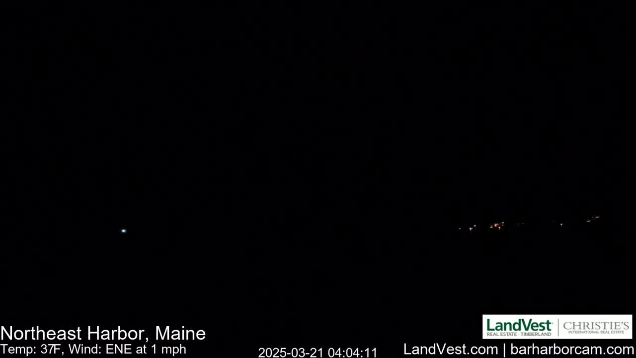 A dark, nighttime scene shows a few distant lights on the horizon under a clear sky, with a temperature of 37°F and a light east-northeast wind.