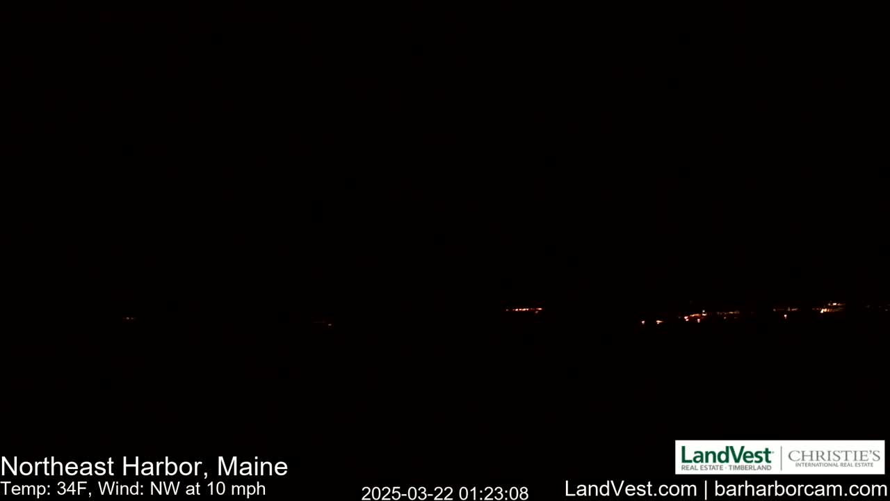 A nighttime long shot of a dimly lit town under a dark, clear sky with a northwest wind of 10 mph and a temperature of 34°F.