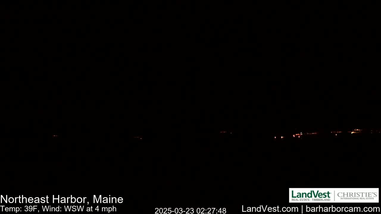 A nighttime long shot shows a dark landscape with a faint line of distant lights under a clear, dark sky, with a temperature of 39°F and a wind of 4 mph from the west-southwest.