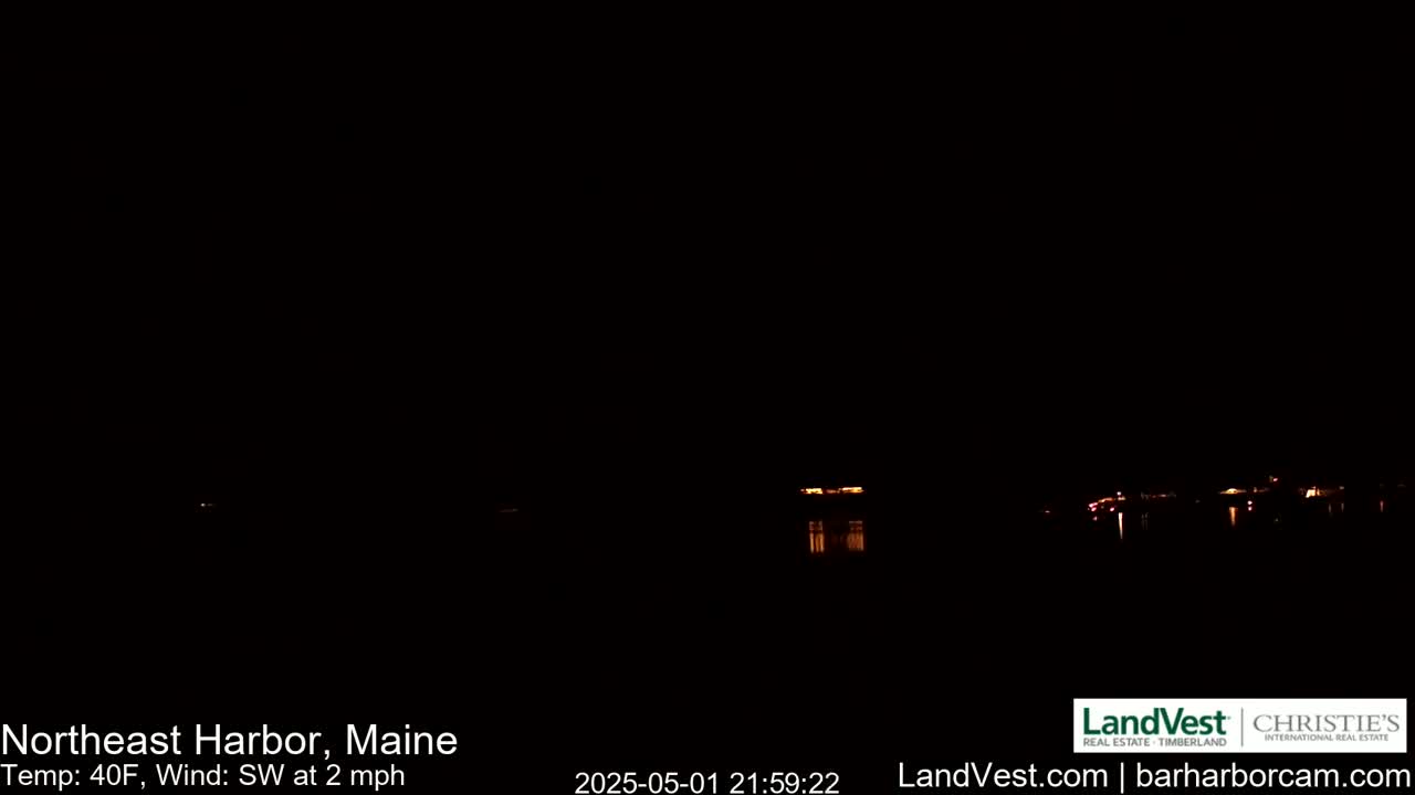 A nighttime view of dimly lit buildings across a dark body of water under a clear, dark sky with a southwest wind blowing at 2 mph and a temperature of 40°F.