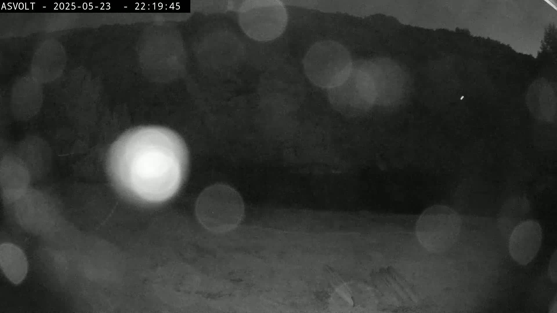 A blurry nighttime image shows a dark, indistinct landscape with out-of-focus lights.