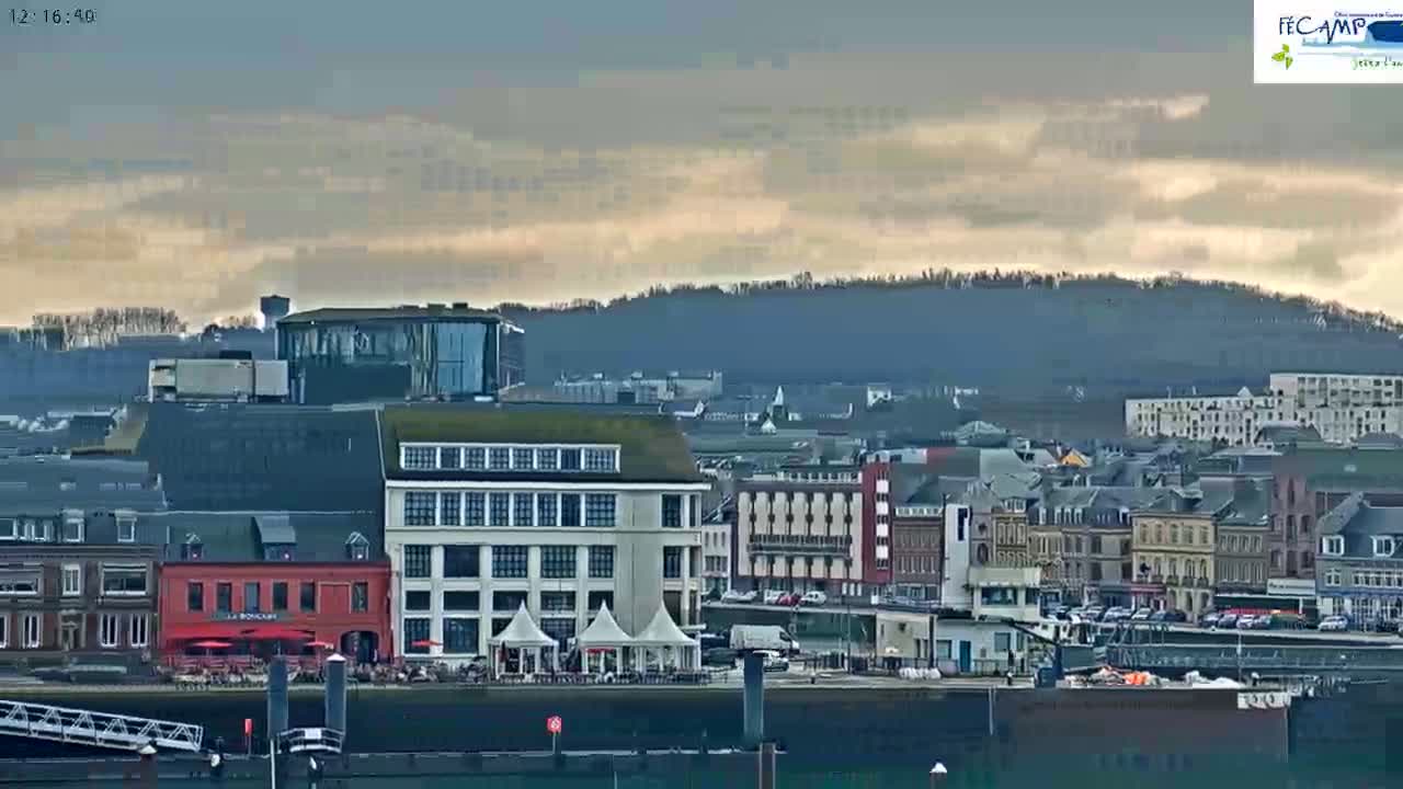 A waterfront town with overcast skies and hills in the background.