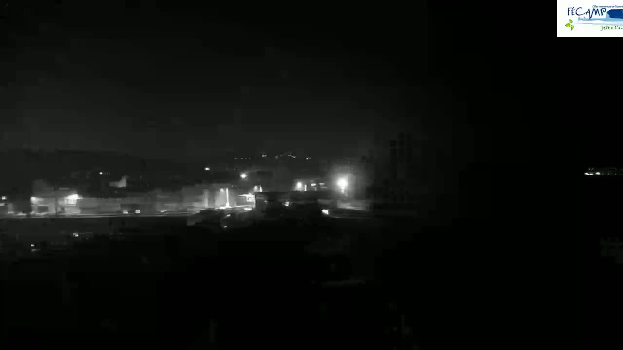 A nighttime, low-light view of dimly lit buildings and vehicles in the distance.