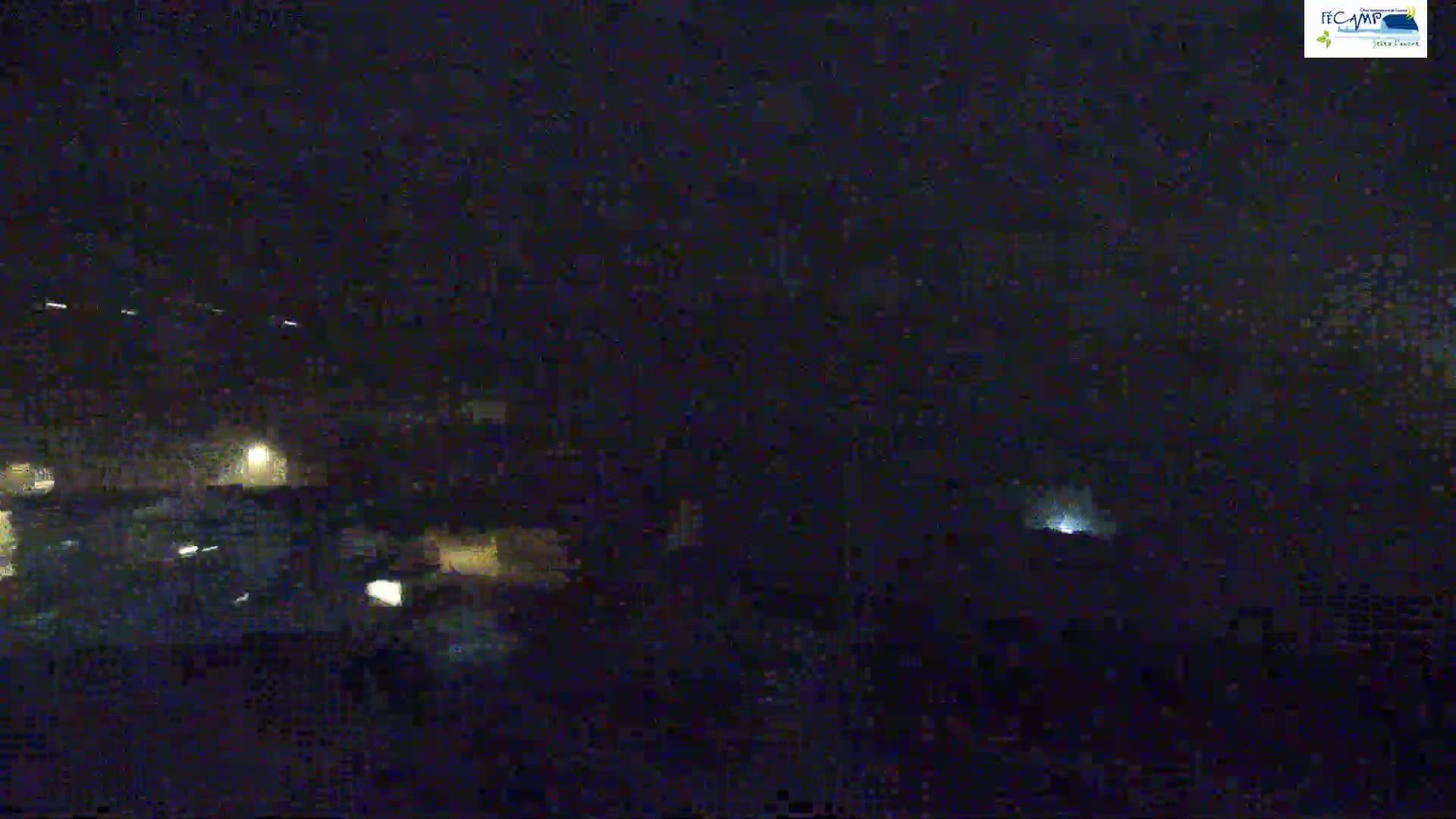 A nighttime, low-light view of a dimly lit area, possibly a town or city, with faint lights visible in the darkness.