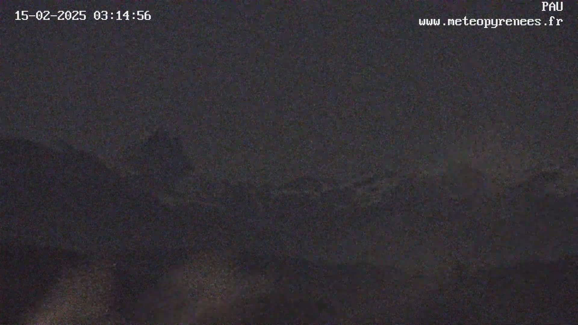 A nighttime, dark image shows a blurry, indistinct view of a mountainous landscape under a dark sky.