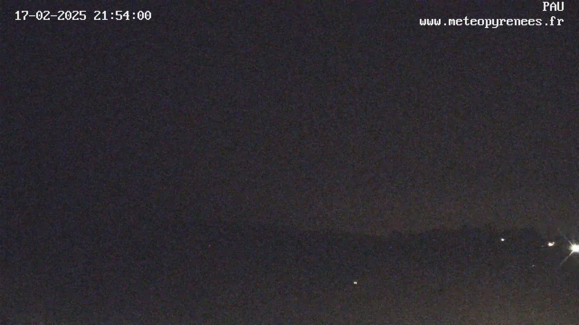 A nighttime outdoor scene shows a dark sky with a few distant lights visible on the horizon.