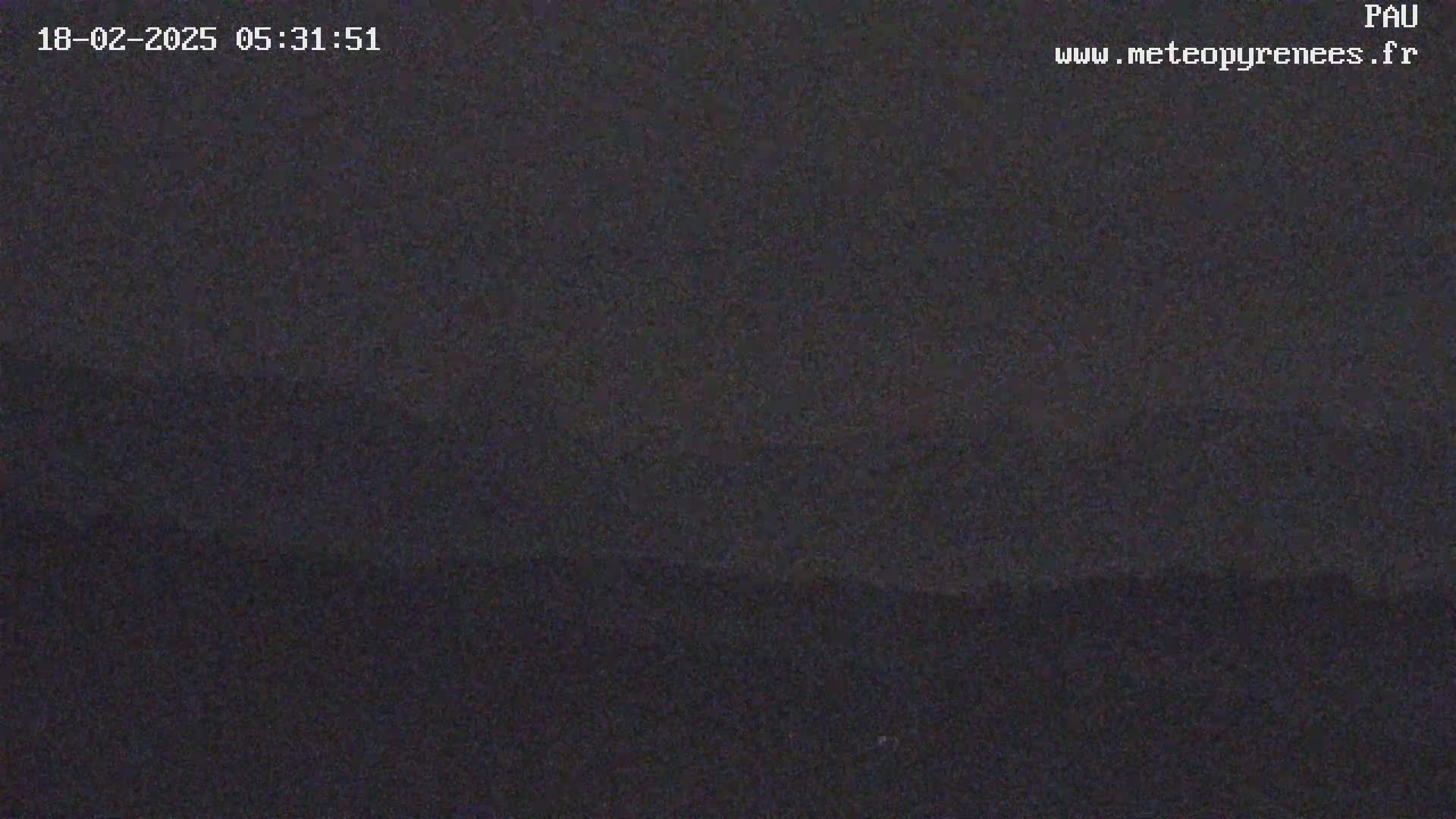 A dark, possibly nighttime, outdoor scene shows a mostly uniform dark gray or black expanse, possibly a sky or flat landscape.