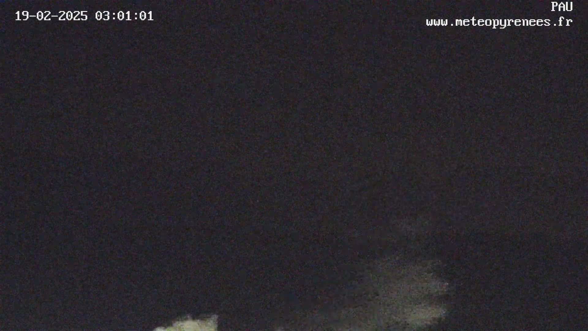 A low-light nighttime image shows a dark sky with faint, light-colored clouds or mist near the bottom.