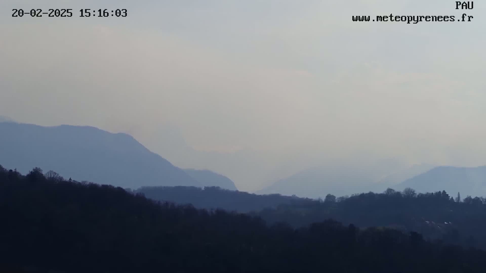 A hazy view shows rolling hills and mountains under a light, overcast sky.