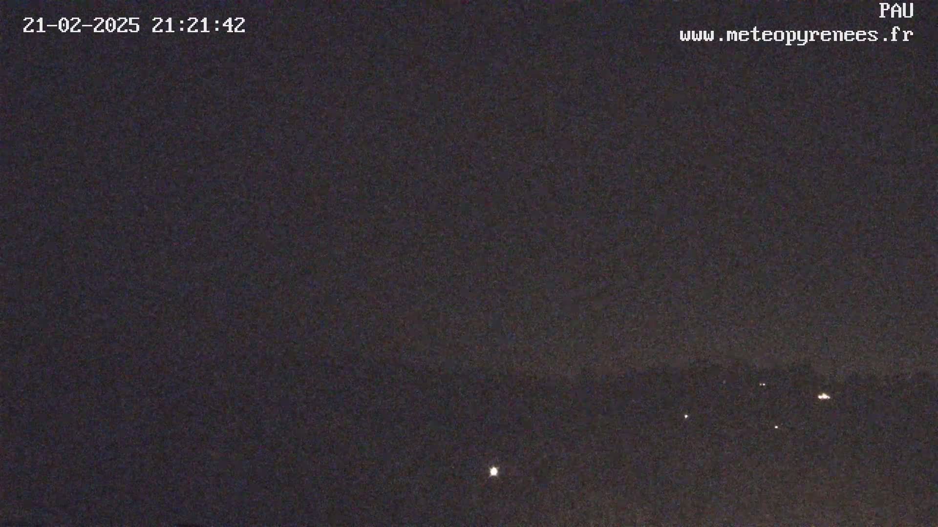 A nighttime, dark sky shows a few distant lights on the horizon.