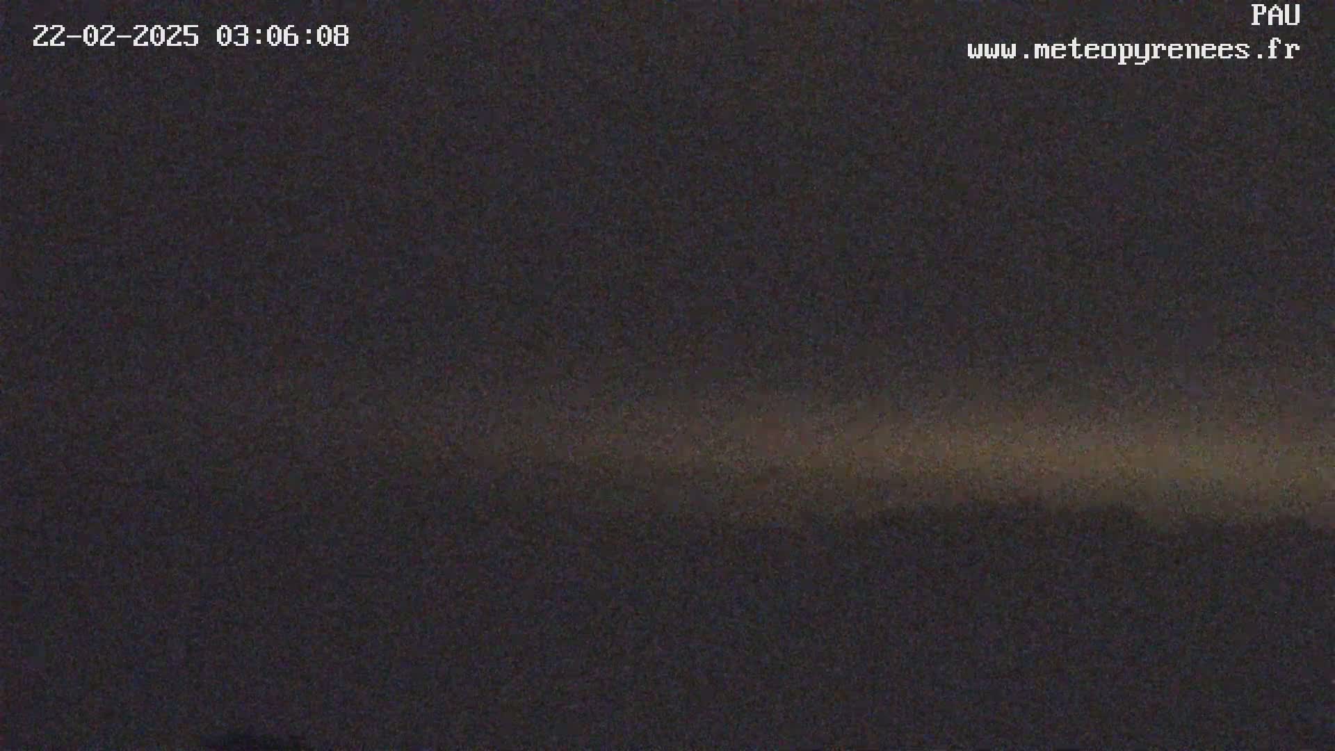 A dark, nighttime scene with a faint, horizontal band of lighter color near the horizon.