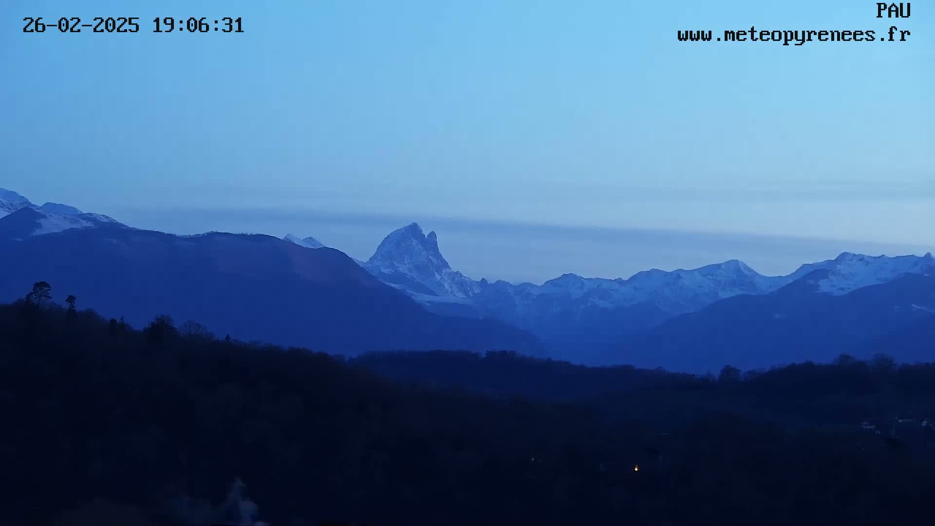 Silhouetted mountains, some snow-capped, are visible under a twilight blue sky.