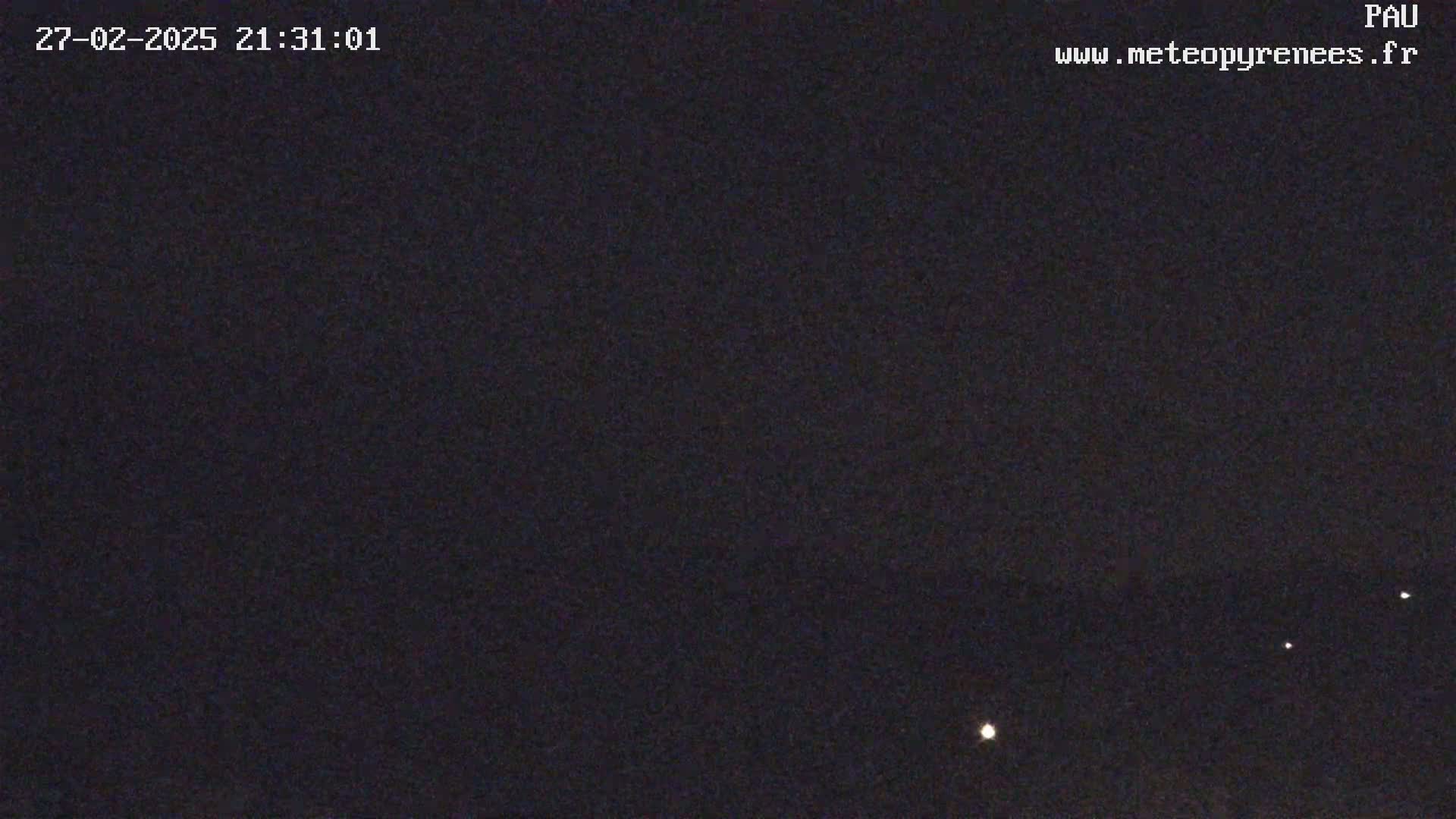 A nighttime image shows a dark sky with a few distant lights visible.