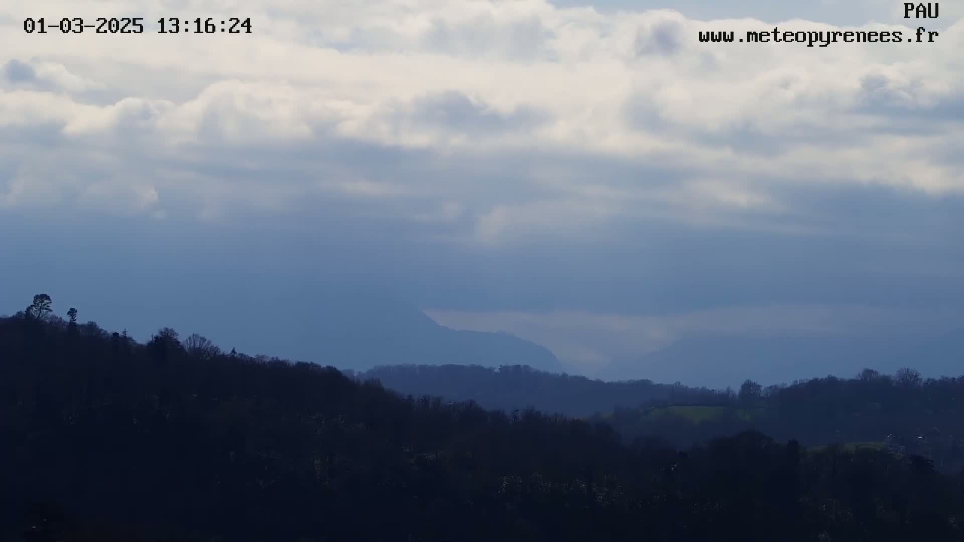 A partly cloudy sky overlooks a range of dark, silhouetted hills and mountains.