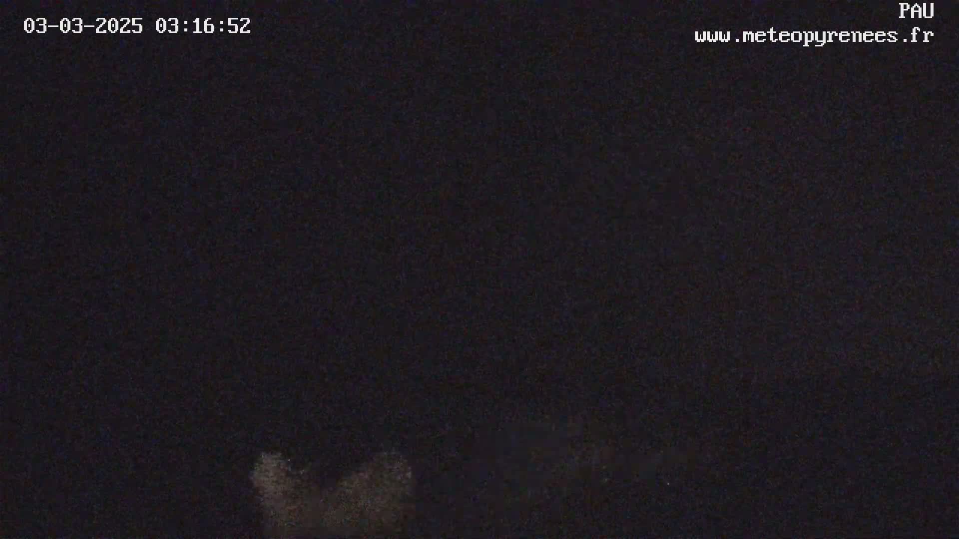 A nighttime image shows a low-light view of what appears to be a mostly clear night sky with some indistinct features near the bottom.