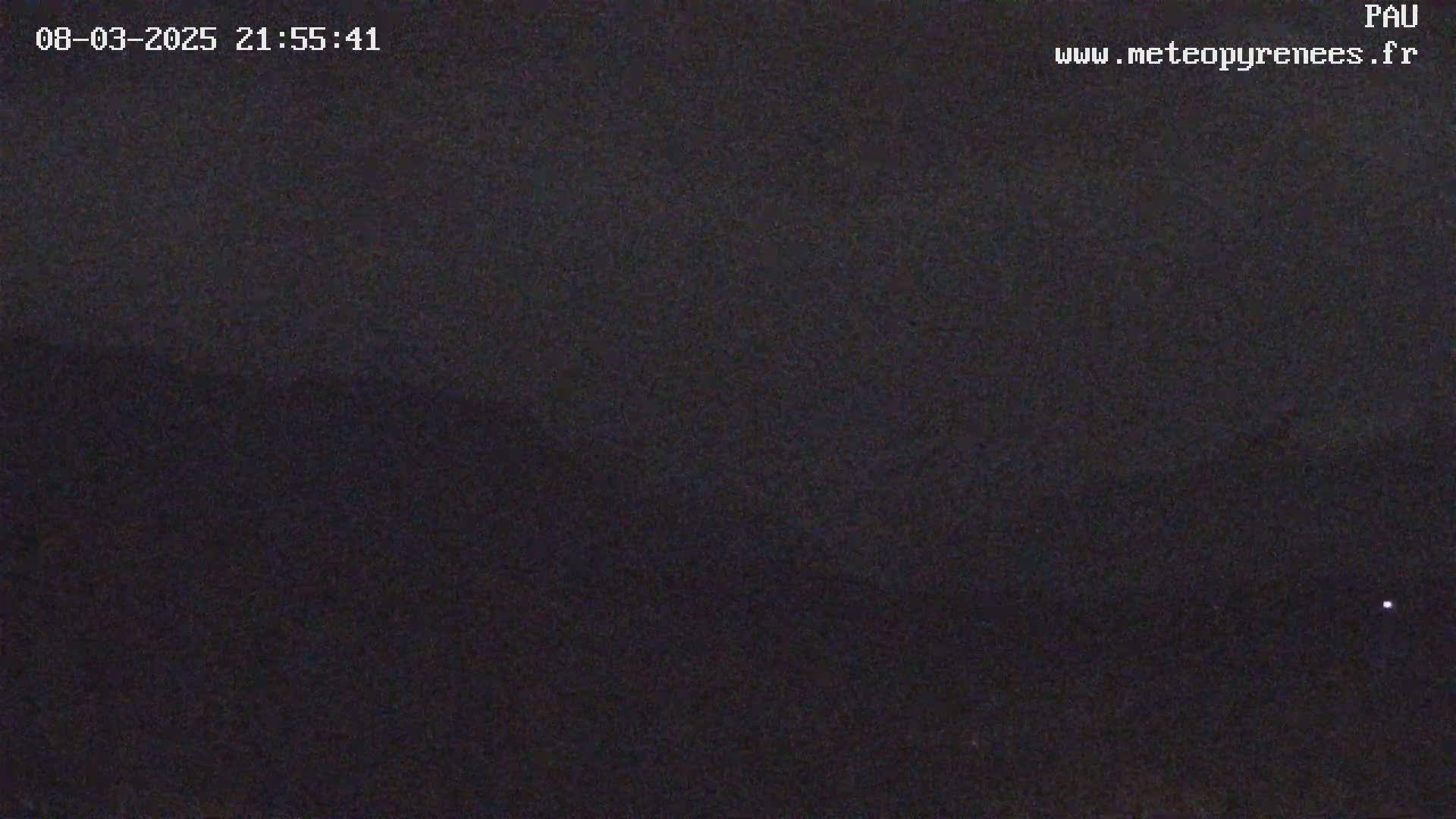 A dark, nighttime scene with a mostly clear sky, showing only a single faint light in the distance.