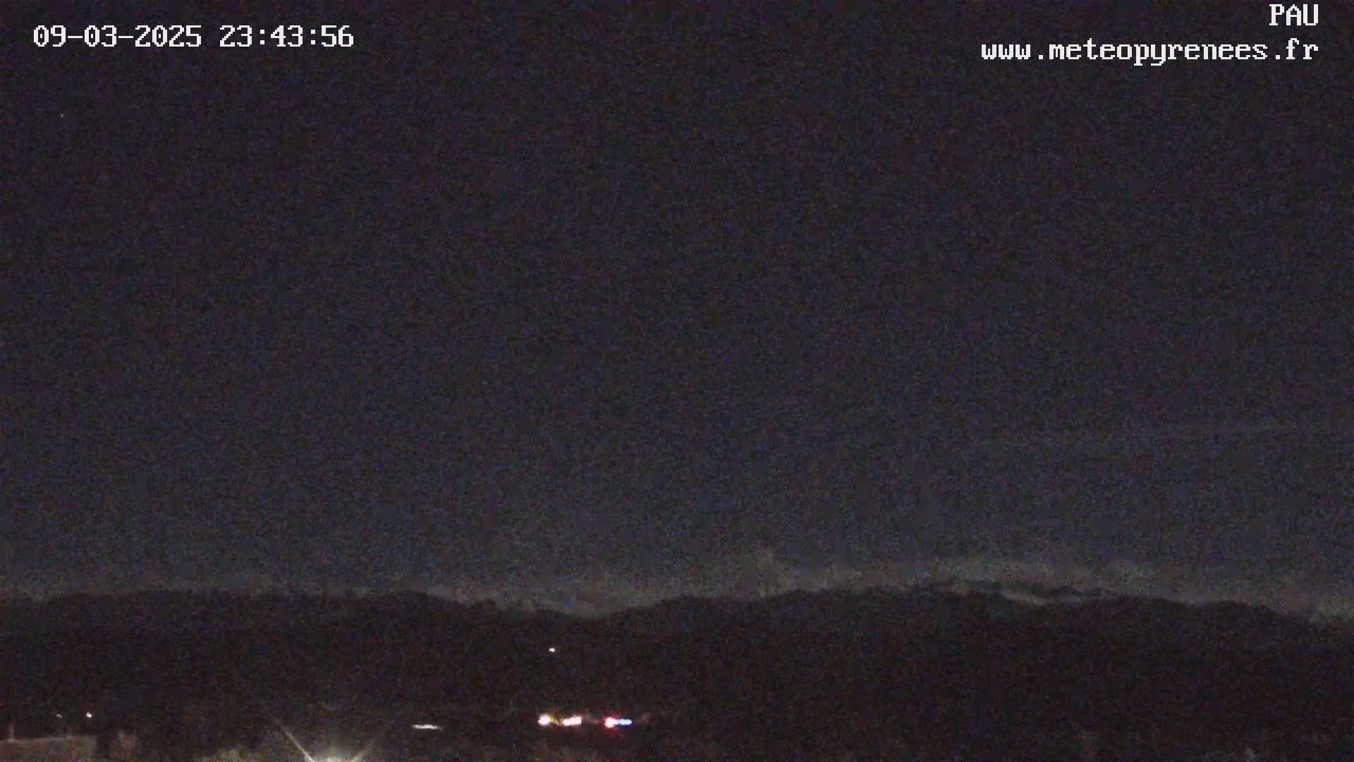 A nighttime view of a dark mountain range under a clear, starless sky.