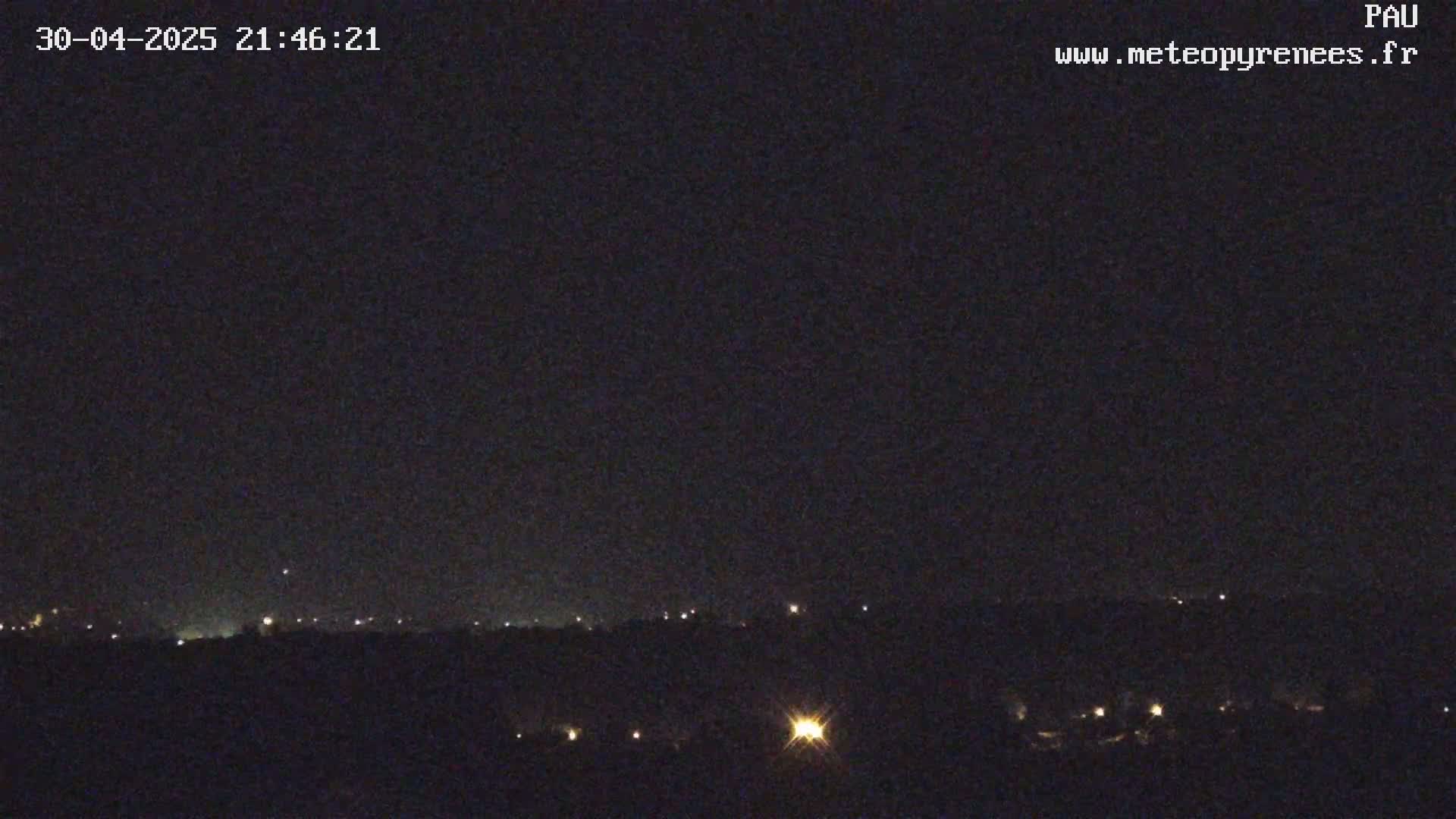 A nighttime, clear view of a distant town with scattered lights below a dark sky.