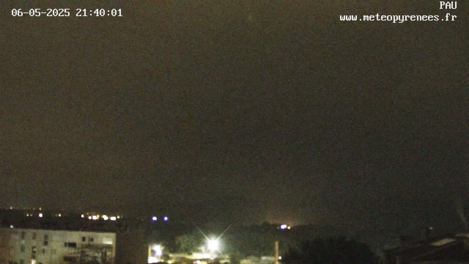 A nighttime view of a city skyline under a dark, clear sky, with some distant lights visible.