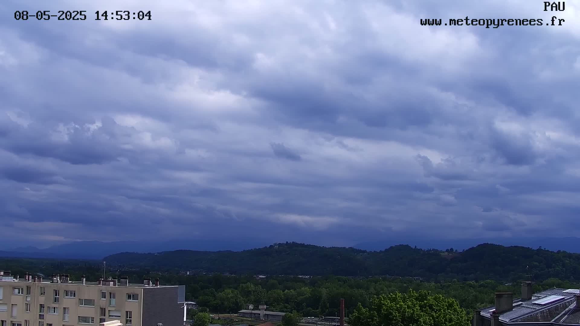 A view of a city and distant mountains under a mostly cloudy, overcast sky.