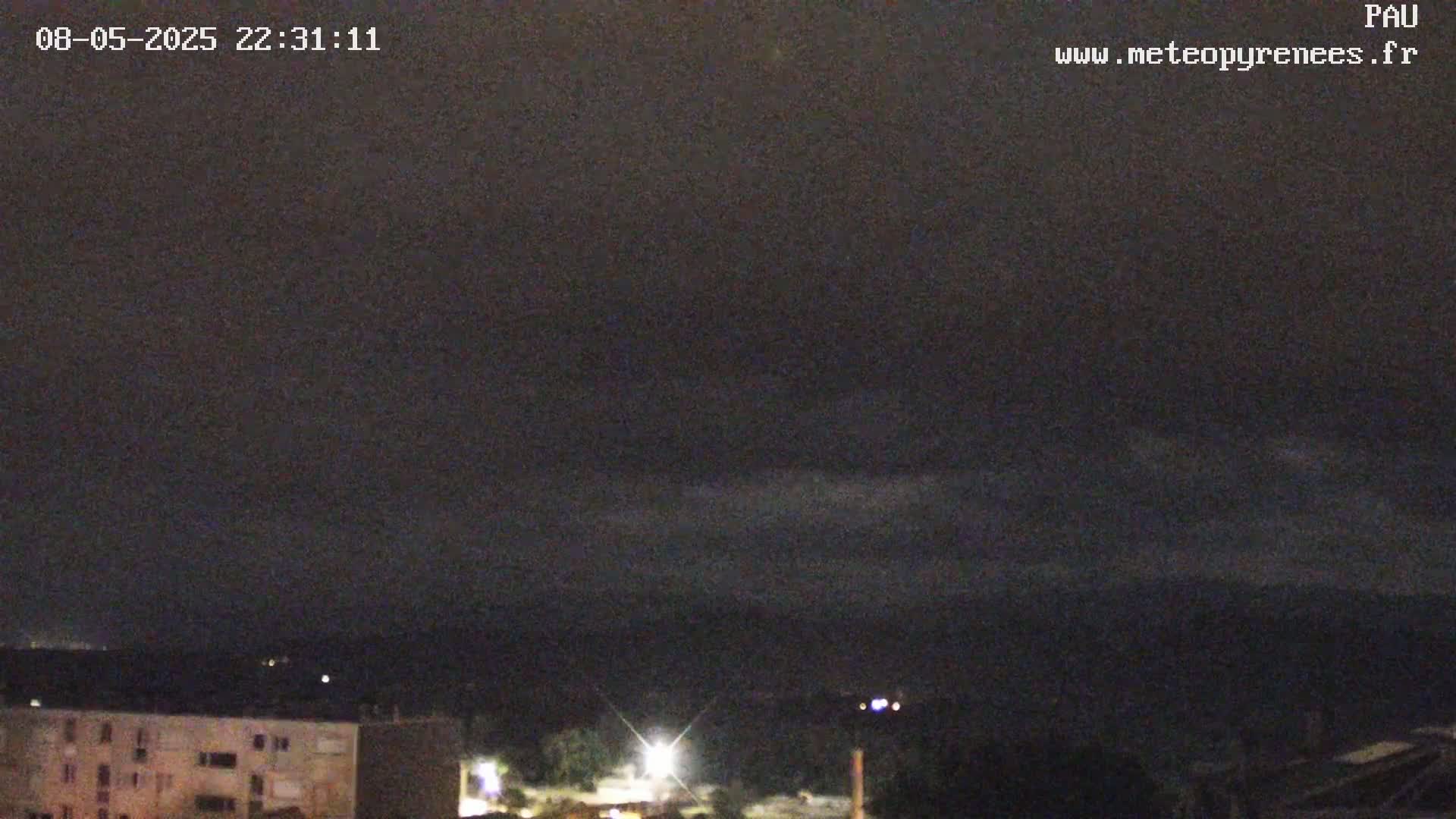 A nighttime view of a city skyline under a dark, cloudy sky.
