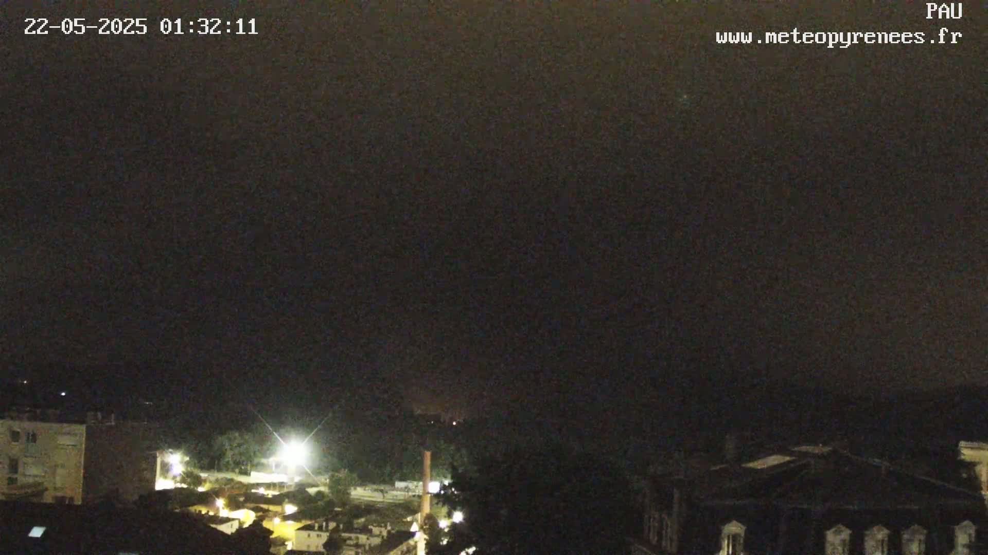 A nighttime view of a town with some lights visible under a dark, overcast sky.