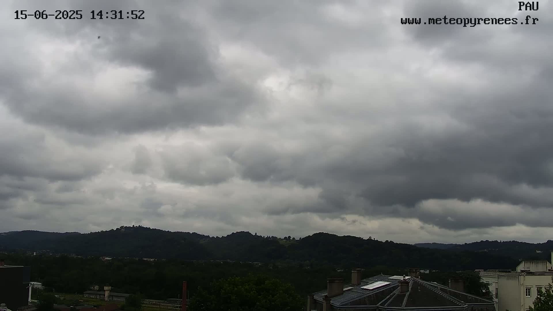 Overcast skies loom over a landscape of dark green hills and rooftops.