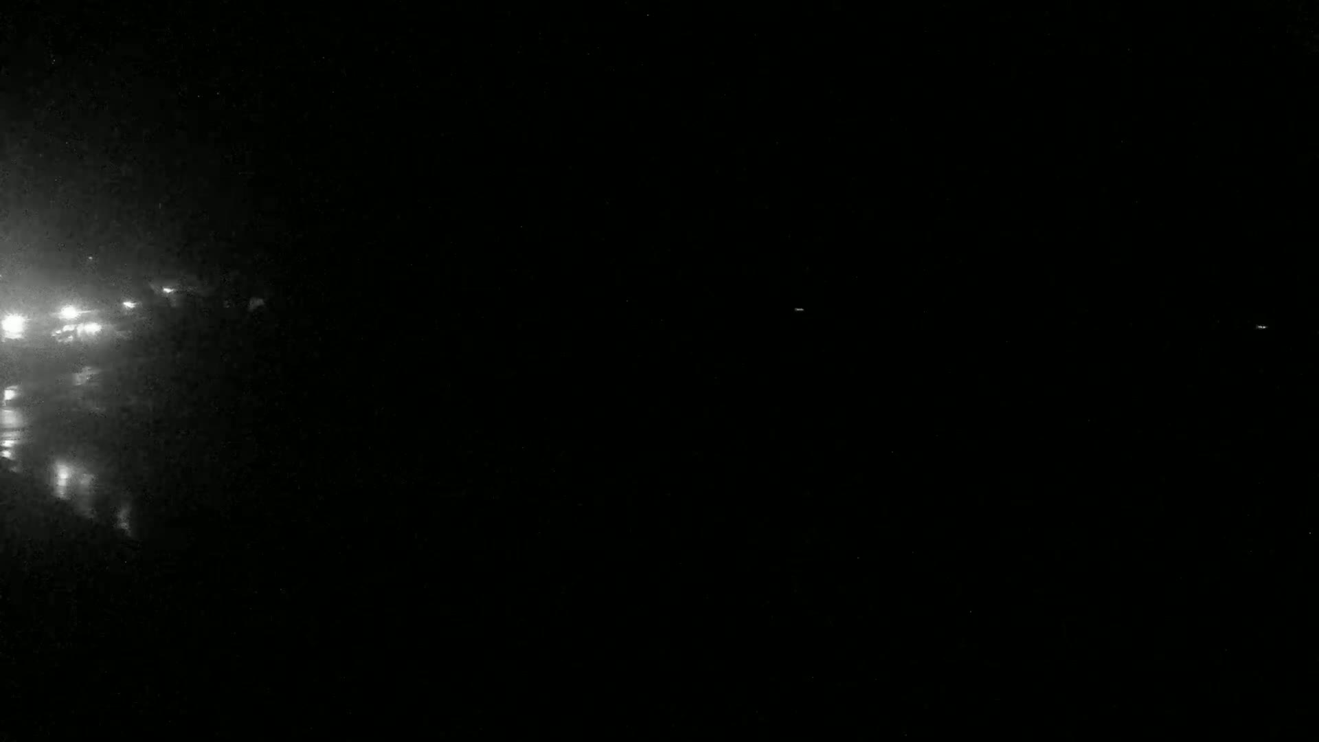Faint lights from vehicles are visible in the dark, possibly at night.